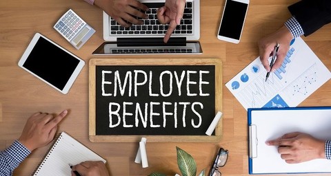 Chalkboard with Employee Benefits on it staged next to an open laptop.