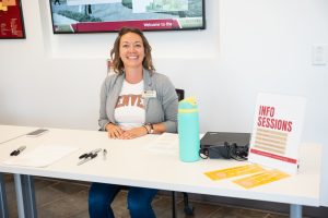 Stacey Stevens, director of Student Employment, sits behind a small table and smiles in a welcoming fashion