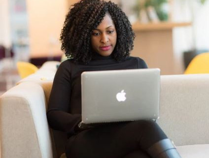 Women on coach using laptop.