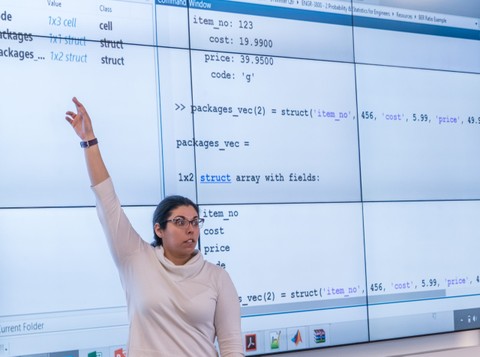 Person presenting and pointing to content on a screen