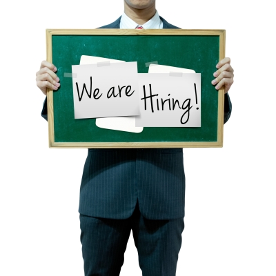 Picture of a person in a suit holding a sign that says We are hiring.
