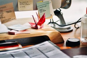 Post-its and a paper crane on a desk.